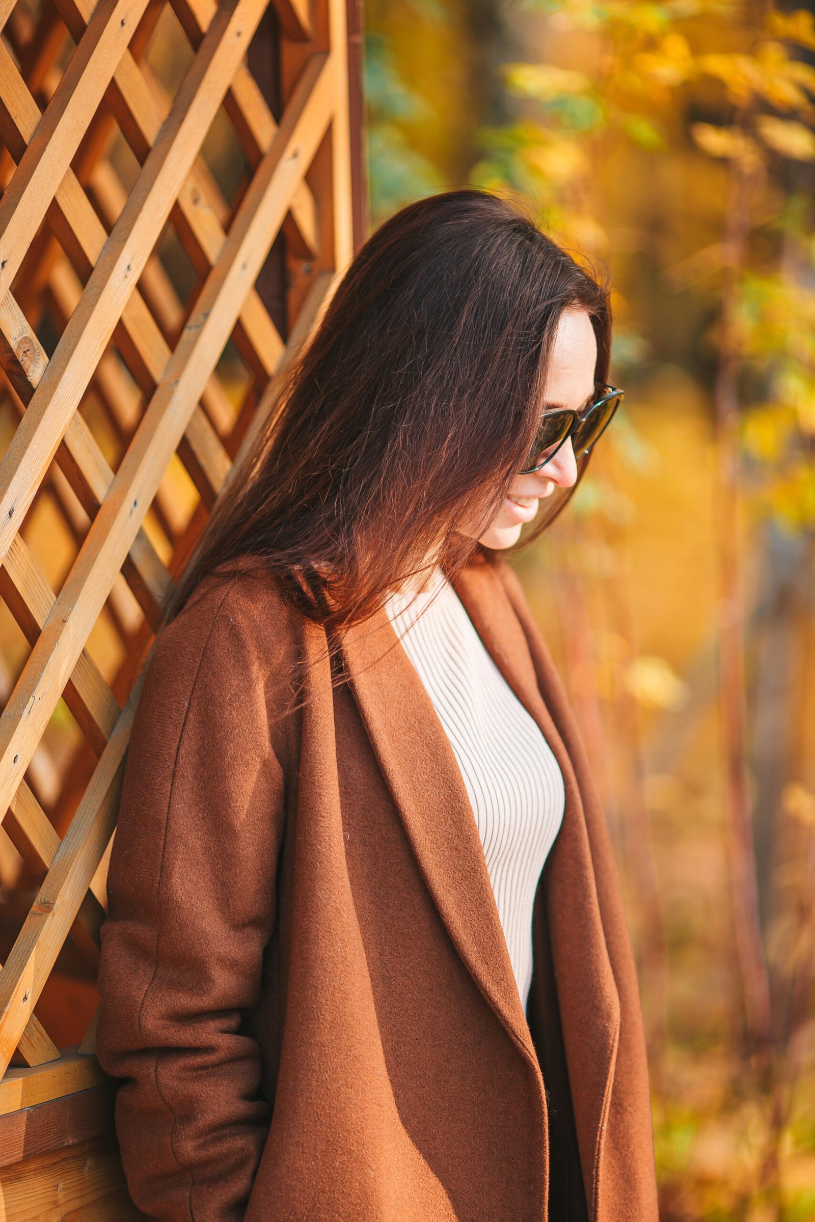 Beautiful woman in brown coat outdoors at autumn